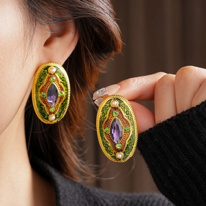 Detailed view of vintage baroque gold earrings with green enamel and purple gemstones
