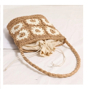 Detail of woven straw bag with white crochet daisy flowers and cotton drawstring liner