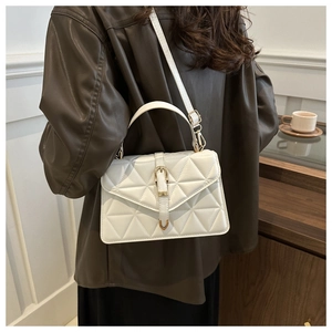 Rear view of model wearing a white quilted crossbody bag with metal buckle and top handle