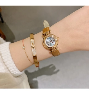 Close-up of elegant gold ladies quartz watch with Roman numerals and brown leather strap