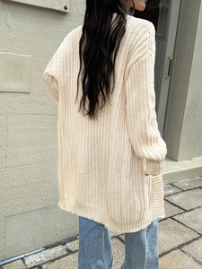 Cardigan lungo da donna in maglia grossa beige abbinato a jeans in luce naturale calda