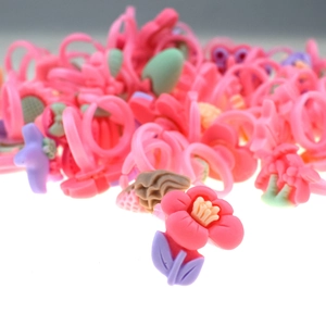 Close-up of pink flower shaped plastic ring for girls with blurry background of colorful rings