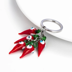 Red chili glass key ring with blue evil eye charms on a ceramic white plate
