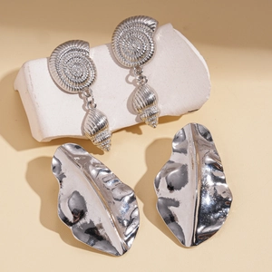 Silver shell pattern and leaf drop earrings on white stone stand for women