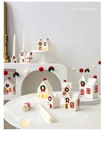 Detailed view of white ceramic Christmas house ornaments with festive wreath patterns