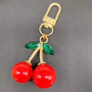 Charming red cherry keychain with green crystal leaves and gold-tone metal hook