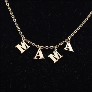 Close-up of gold MAMA letter pendant necklace on black velvet display background