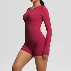 Détail d'un ensemble de yoga magenta sans couture avec haut à manches longues et short taille haute