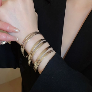 Close-up of minimalist gold and silver cuff bracelets with hammered metal textures