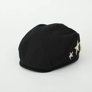 Detail of a black kids beret with star embroidery and side brand tag on cotton fabric