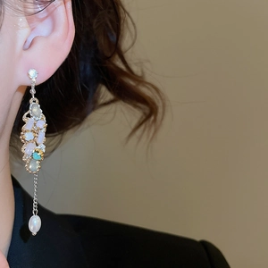 Detail of silver long tassel earrings with multicolored stones and teardrop pearl on model