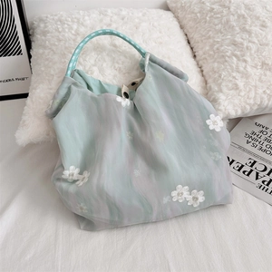 Detail of light green floral silk tote with white 3D embroidery and woven handle