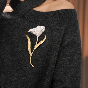 Detail of tulip flower brooch with gold leaves and silver petals on black knitwear