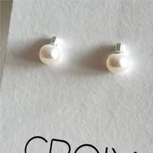 Close-up of minimalist freshwater pearl earrings on a white textured card display