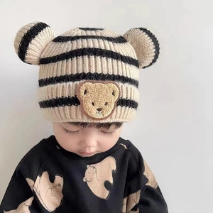Détail d'un bonnet tricoté pour bébé à rayures beige-noir avec oreilles d'ours