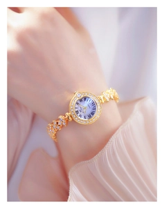 Close-up of gold tone women's watch with rhinestone bezel and Roman numeral dial