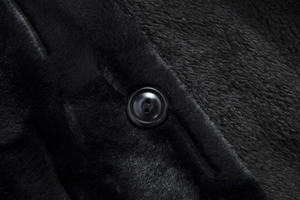 Detailed macro view of black faux fur fabric texture with a circular resin button