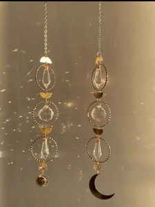 Detail of sun and moon crystal suncatchers casting rainbow light spots on wall