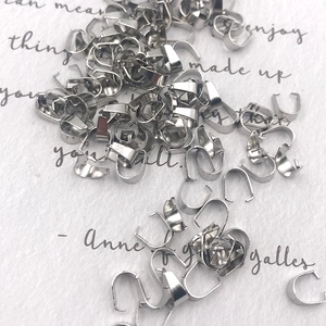 Polished silver stainless steel pendant pinch bails stacked on aesthetic background
