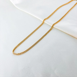 Detailed close-up of a 14k gold-plated Cuban link chain on a white silk background