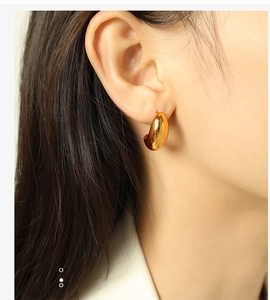 Detail showing high-polish gold teardrop hoop earring on model with mirror finish