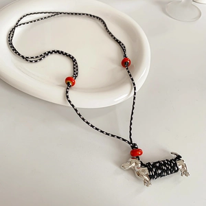 Detail of woven rope necklace with silver dachshund pendant and decorative red beads