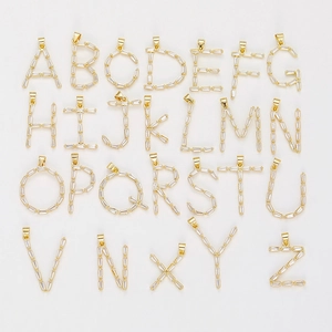 26 goldene Buchstabenanhänger mit Zirkonia-Steinen ordentlich auf weißem Grund angeordnet