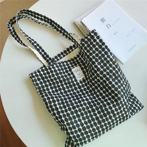 Flat lay of black and white geometric pattern cotton tote bag on white table with book