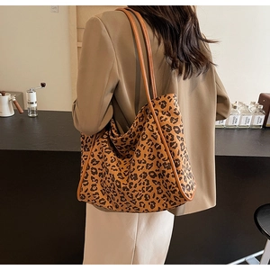 Detail of leopard print tote bag with brown leather straps worn by model in a cafe