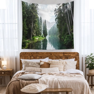 Nature landscape wall tapestry featuring forest and snow mountains over a bedroom bed