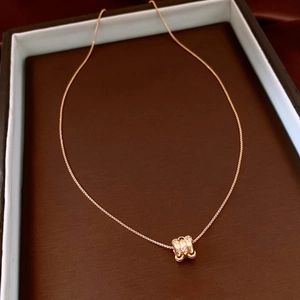 Close-up of 18k gold plated necklace with diamond-accented cylinder pendant in a box