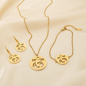 Close-up of gold MOM pendant and steel jewelry set on soft beige fabric
