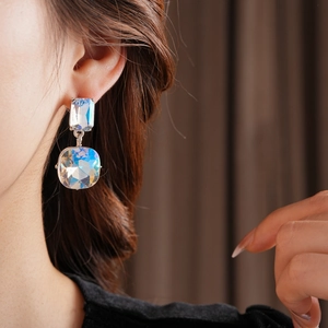 Macro view of crystal square tassel earrings in iridescent colors on model
