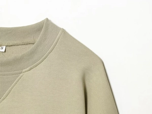 Gros plan détaillé de l'encolure du sweat-shirt en coton vert olive avec coutures doubles
