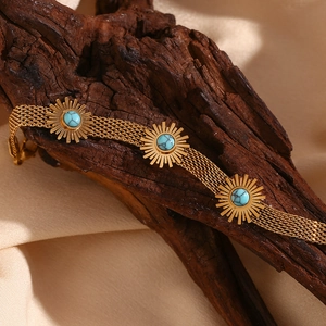 Vintage 18K gold plated mesh bracelet with turquoise sunburst charms on a wooden base