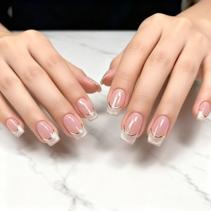 Faux ongles French nude carrés avec bouts pailletés argentés et fil doré élégant