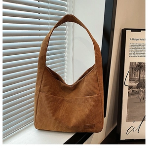 Detail of a brown corduroy tote bag featuring a front pocket and soft textured material