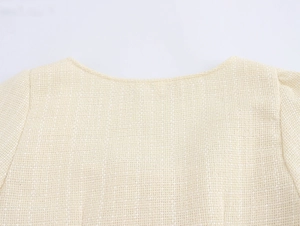 Détail de la texture du tissu en tweed beige et de l'encolure de la robe élégante
