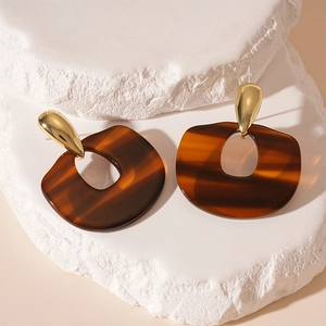 Détail macro de boucles d'oreilles en résine léopard sur pierre blanche et lumière naturelle