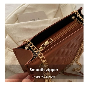 Detail of smooth gold zipper and embossed diamond texture on a brown chain bag