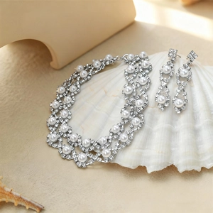 Close-up of pearl and rhinestone jewelry set displayed on a white seashell