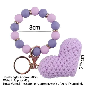 Knitted heart keychain with purple and pink silicone beads on a white background