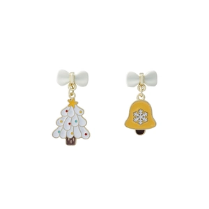 Detail of Christmas tree and bell asymmetric earrings with festive bows on white background