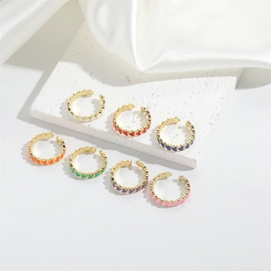 Close-up of seven colorful enamel heart rings with adjustable open bands on white fabric