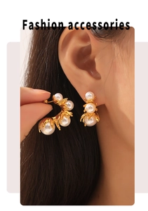 Detail of elegant C-shaped gold titanium earrings with inlaid white pearls on model