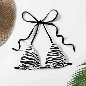 Zebra print halter bikini top with adjustable black ties on a beach-themed background