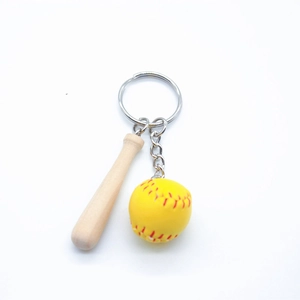 Close-up of mini wooden baseball bat and yellow softball keychain with silver ring