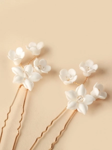 Close-up of bridal hair pins with white ceramic flowers and crystal accents on gold U-shaped pins