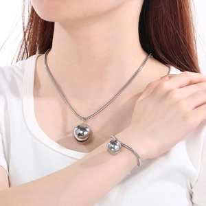 Macro view of silver snake chain necklace and bracelet set with hollow ball pendant