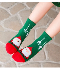 Close-up of green Christmas socks with Santa Claus pattern on soft knitted cotton